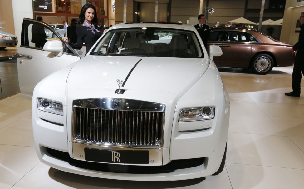 A staff member poses at a Rolls-Royce Ghost extended wheelbase car during a press preview day at the AMI Auto Show in Leipzig
