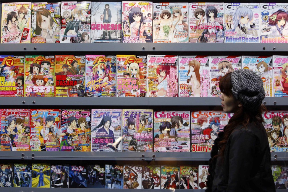A booth assistant looks at 'manga' or cartoons displayed at Japanese publishing company ASCII Media Works' booth during a photo opportunity at the Tokyo International Anime Fair