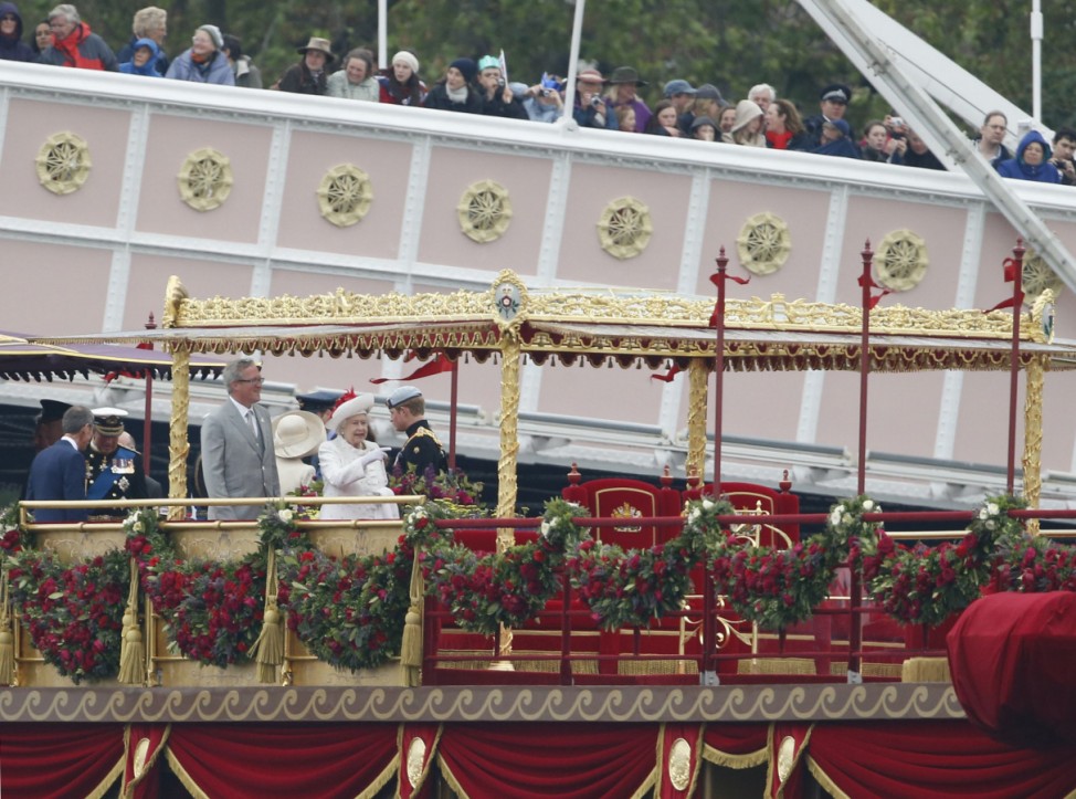 Britain's Queen Elizabeth points down river while standing on the royal barge on the River Thames, in London
