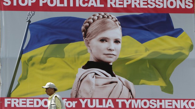 A man walks past a board with a portrait of jailed former Ukrainian Prime Minister and opposition leader Yulia Tymoshenko in central Kiev