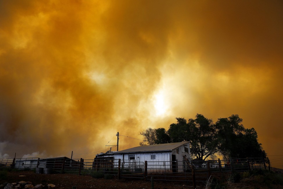 Smoke fills the air over a small barn turning the sky orange as the High Park Fire burns near Laporte, Colorado