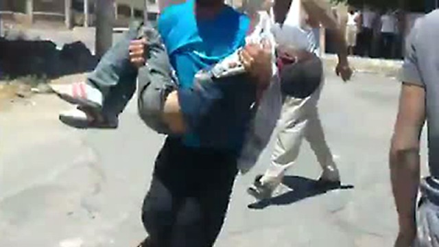 Bericht der Vereinten Nationen: Dieses Bild aus einem Video syrischer Aktivisten soll eine Szene aus der Stadt Daraa zeigen: Ein Mann trägt einen verletzten Jungen zu einem Krankenwagen.