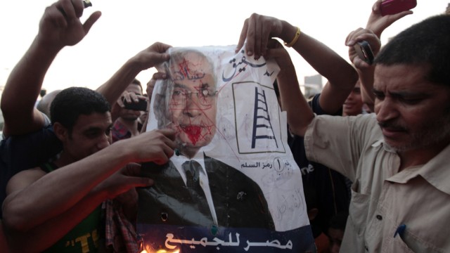 Protesters burn a defaced poster of presidential candidate Shafik at Tahrir square in Cairo