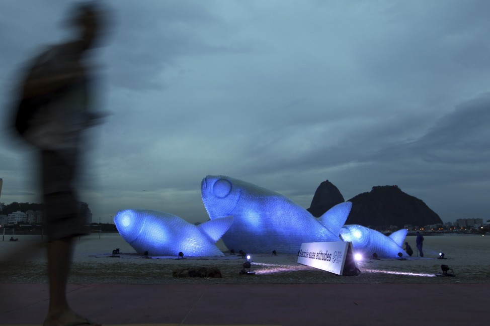 Man walks past giant fish made with plastic bottles exhibited at Botafogo beach