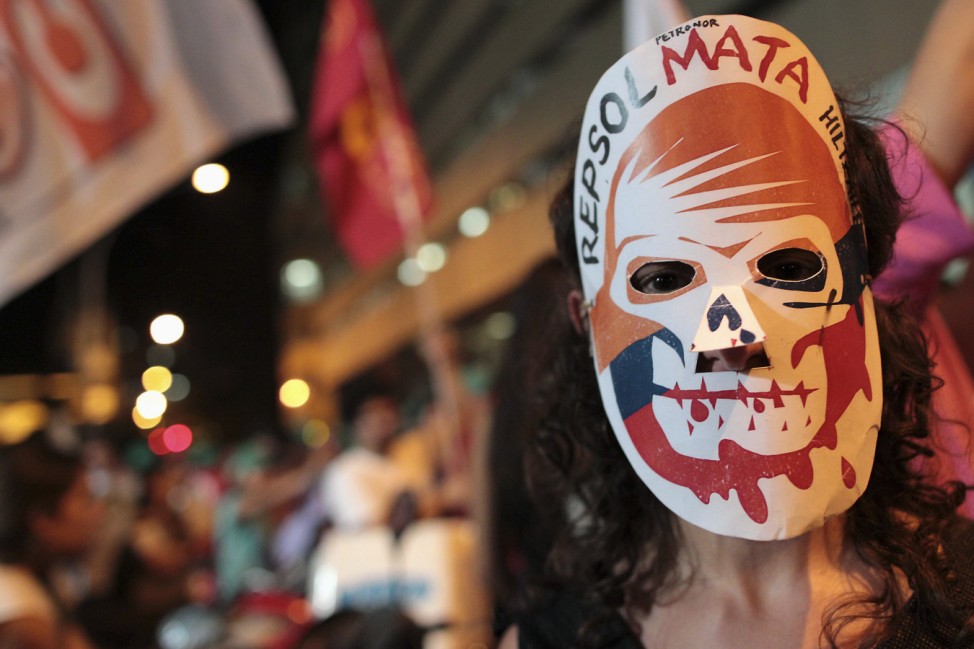 A woman wears a mask protesting against Spanish energy firm Repsol during a demonstration in Rio de Janeiro