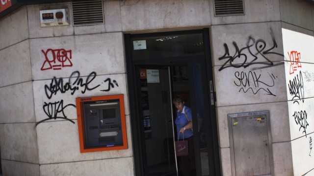 A woman walks out of a Catalunya Caixa savings bank branch in Madrid