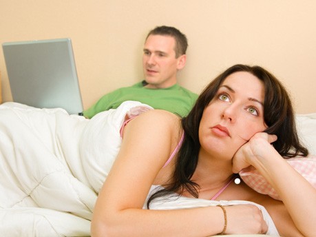 Frau und Mann mit Computer im Bett