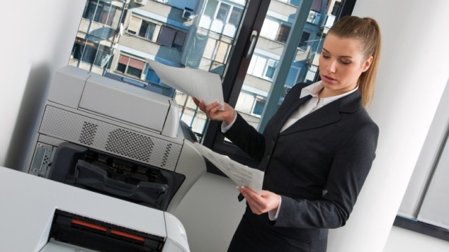 Schadsoftware: Frau am Bürodrucker (Symbolbild): Kauderwelsch aus dem Netzwerkdrucker.