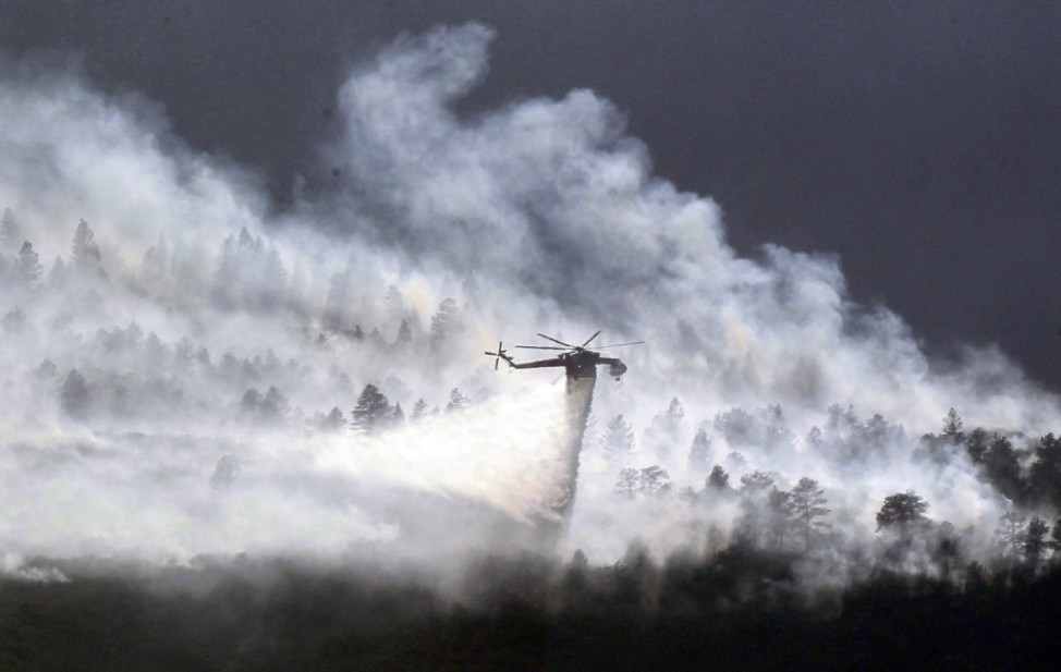 A helicopter drops water on the Waldo Canyon fire burning behind the U.S. Air Force Academy, west of Colorado Springs