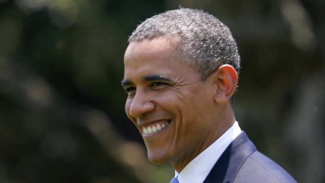U.S. President Obama smiles while he walks towards Marine One at the White House in Washington
