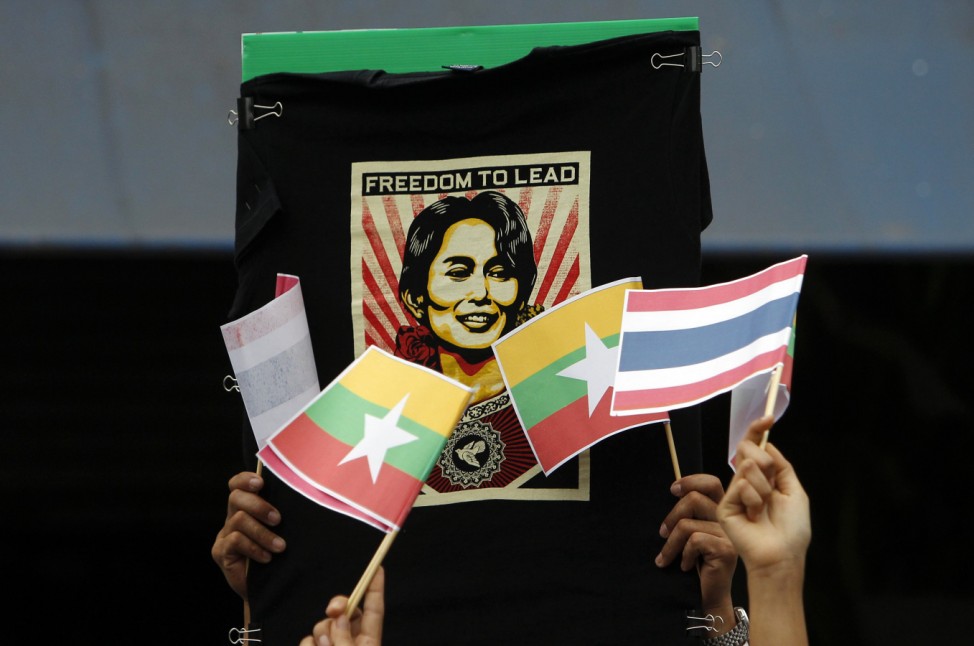 Migrant workers from Myanmar hold an illustration of pro-democracy leader Suu Kyi, along with Thai and Myanmar flags in Samut Sakhon province