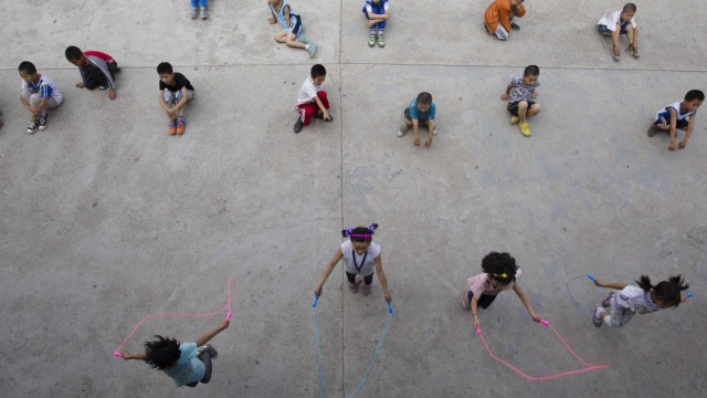 Migration und Kunst: Kinder ausländischer Arbeiter spielen vor einer Schule in Peking: Nicht nur die Identität des Einzelnen, auch die Kunst wird durch Migration geprägt.