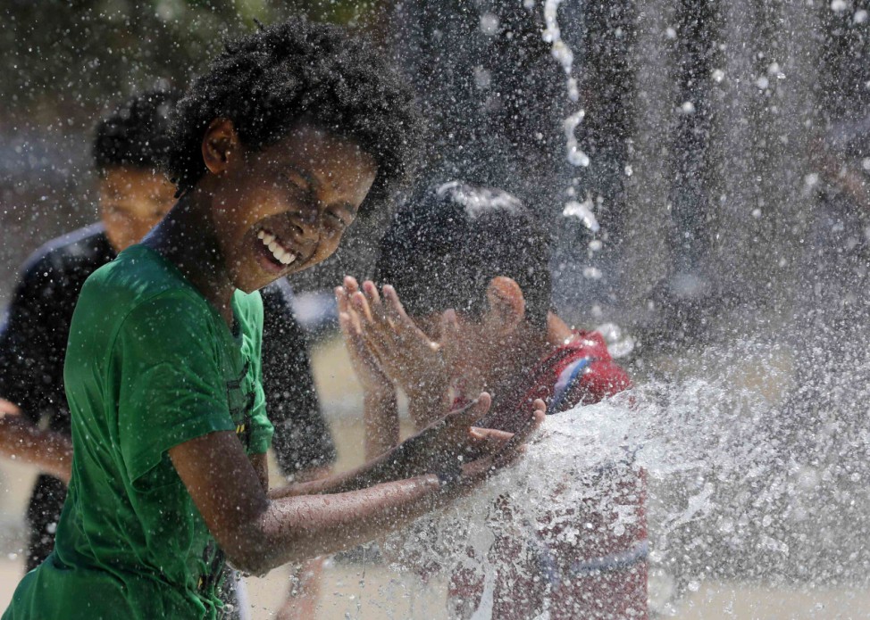 Kids play in a water fountain in the Capital Heights neighborhood to beat heat gripping Washington