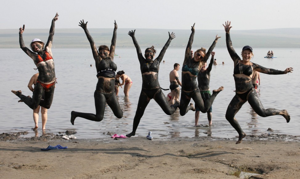 People, covered in mineral-rich black mud, jump while posing for a picture near the Tus lake in Russia's Khakassia region