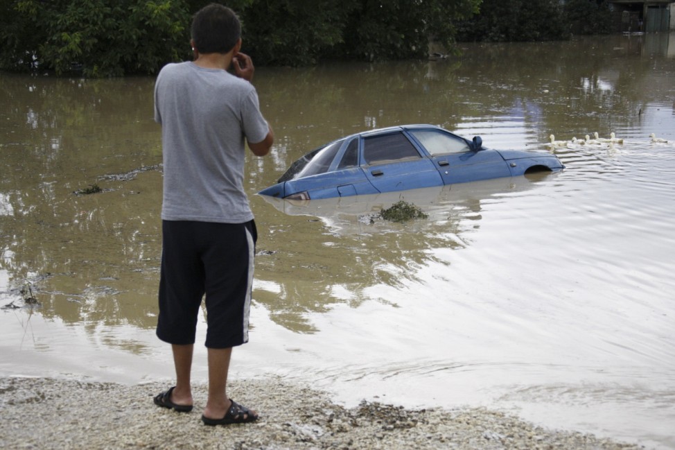 A local resident looks at a submerged car in a flooded street in the village of Novoukrainsk