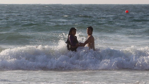A couple swims in the water on a public beach in Alexandria