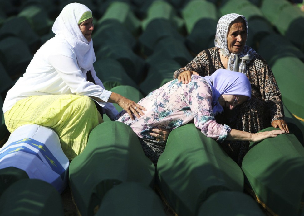 Bosnian Muslim women sit and cry near the coffin of their relatives at Memorial Center in Potocari before a mass burial, near Srebrenica