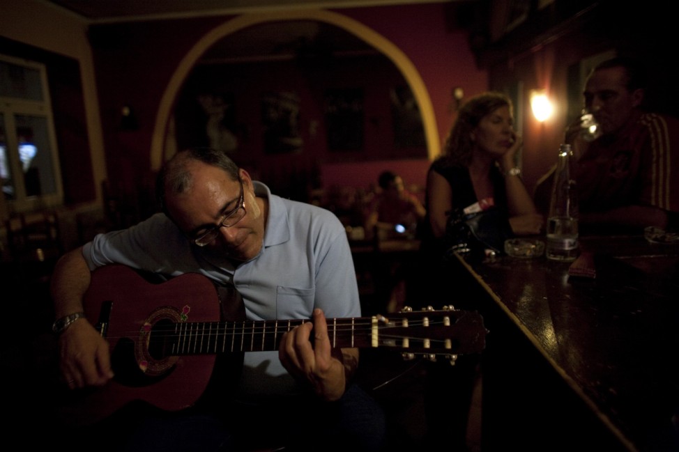 Jose Manuel Abel plays a guitar in the restaurant where he works in Munich