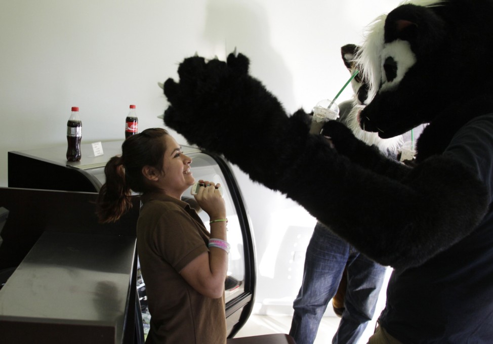 Leo and Adrian, dressed as wolves, share a moment with a barista at a coffee bar in Monterrey