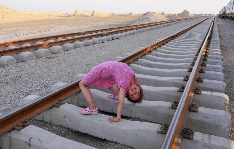 A daughter of a worker plays on a newly-built railway track on the Kumul-Lop Nor line's railway bed in Lop Nor