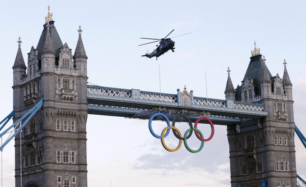 A Royal Navy helicopter carrying the London 2012 Olympic torch flies over Tower Bridge in London