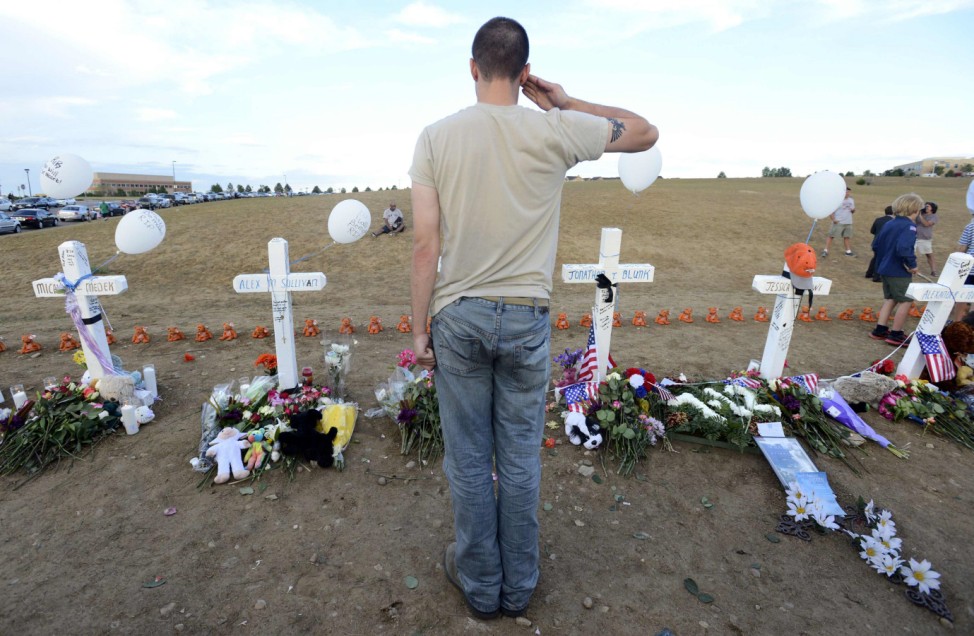 Airman 1st Class Andrew Zayatz salutes a cross with the name of Air Force member Jesse Childres in Aurora