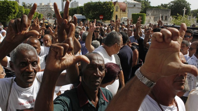 People gesture victory signs as they attend the funeral of Oswaldo Paya, one of Cuba's best-known dissidents, in Havana