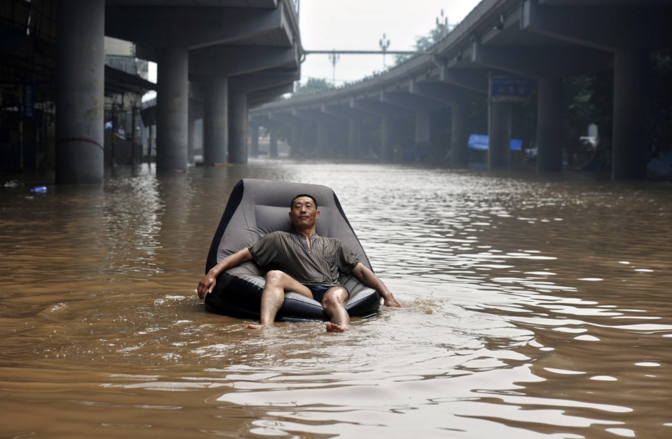 A man takes a nap on an inflatable sofa floating on a flooded street near the Yangtze River in Chongqing municipality