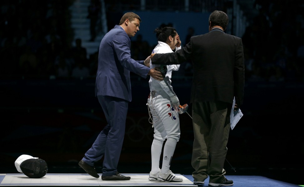 South Korea's Shin reacts as she is escorted after being defeated by Germany's Heidemann during their women's epee individual semifinal fencing competition at the ExCel venue at the London 2012 Olympic Game