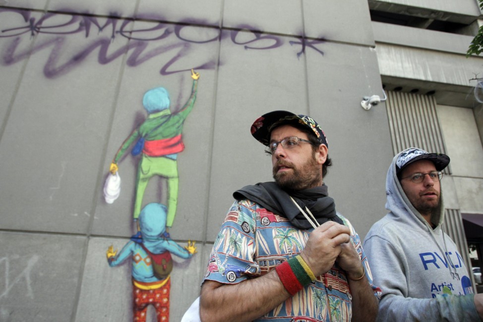 Brazilian Artists Otavio and Gustavo Pandolfo, identical twin brothers who go by the name 'Os Gemeos', speak to reporters in front of a mural at the Revere Hotel Boston Common in Boston