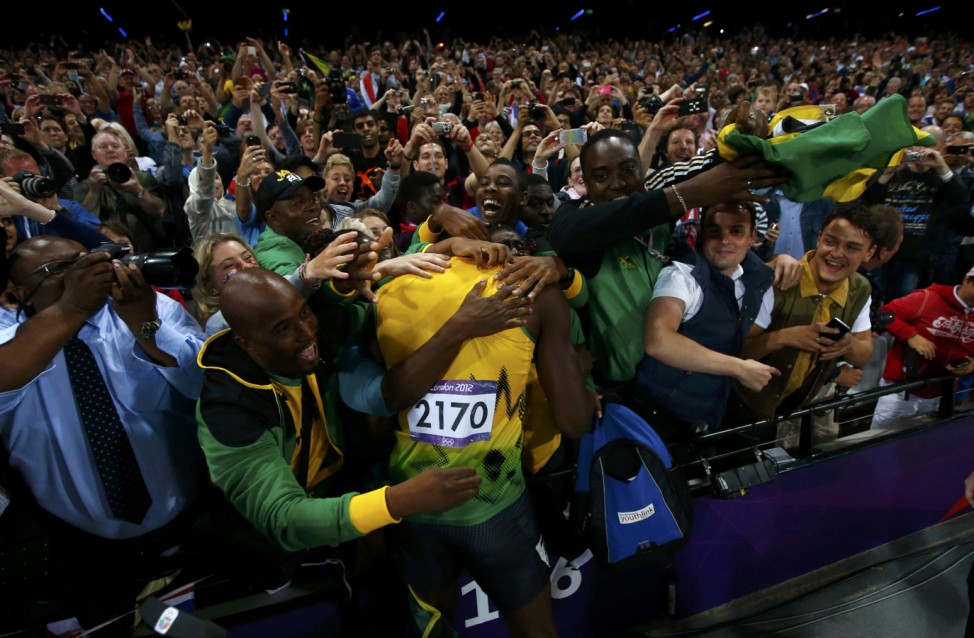 Fans surround Jamaica's Usain Bolt as he celebrates after winning the men's 100m final during the London 2012 Olympic Games at the Olympic Stadium