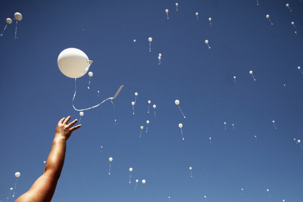 A woman releases a balloon into the air during the 20th anniversary of the closure of the Omarska detention camp in Omarska