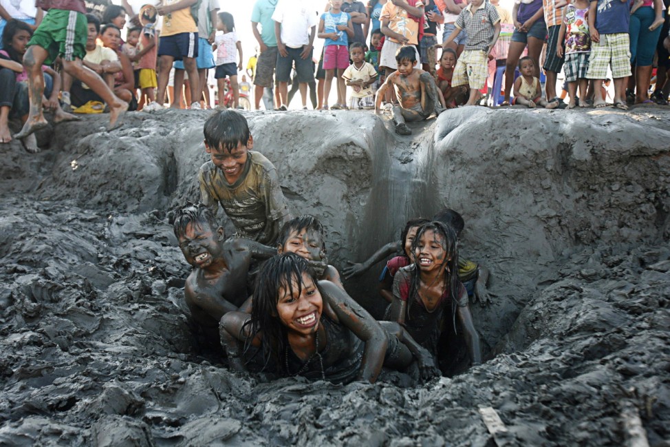 Children play in a mud bank while watching a festival inaugurating the Amazon River as one of seven natural wonders of world at mouth of Itaya River in Iquitos