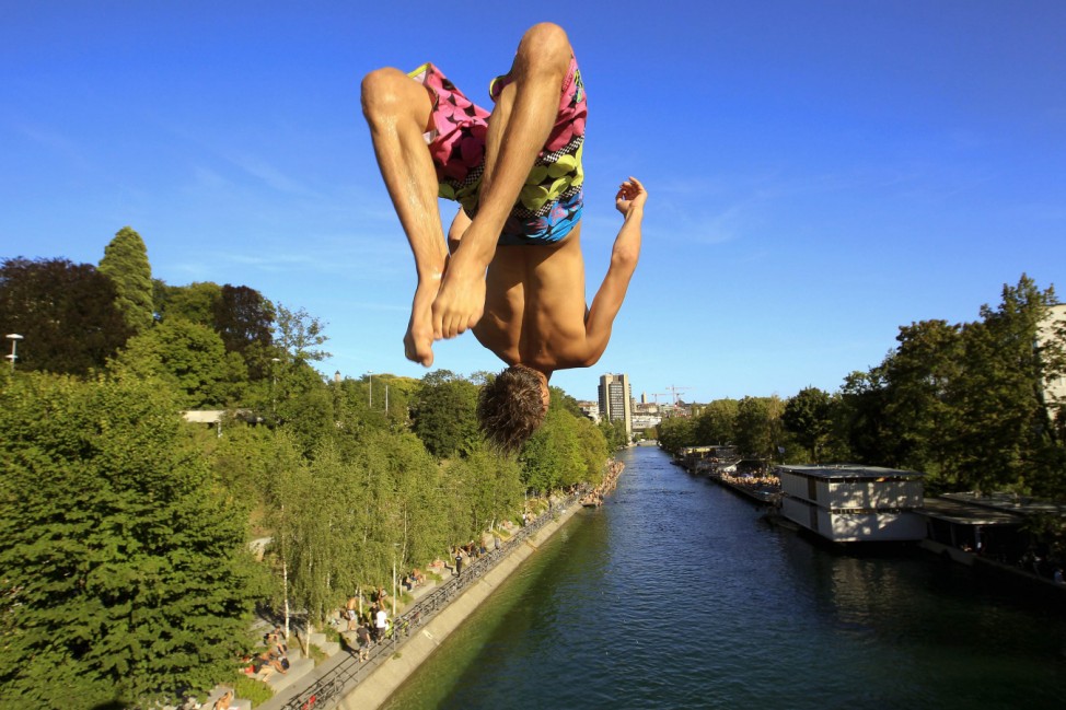 A man jumps from a bridge into the Limmat river during sunny summer weather in Zurich