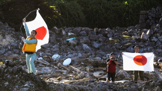 Members of a Japanese nationalist group raise flags as they land on Uotsuri island, part of the disputed islands in the East China Sea