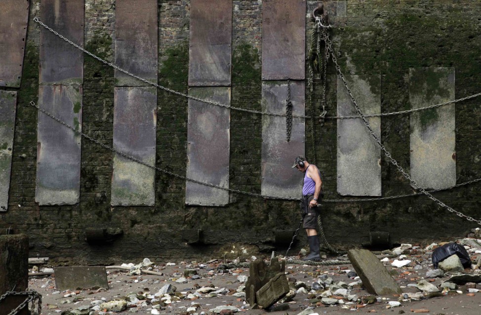 Mudlark 'Mackie' uses a metal detector to search for items of value on the banks of the River Thames in London