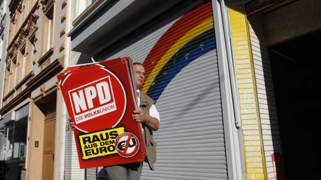 An unidentified man removes placards of the NPD from an office of the banned right-wing extremist group 'Nationaler Widerstand Dortmund' in Dortmund