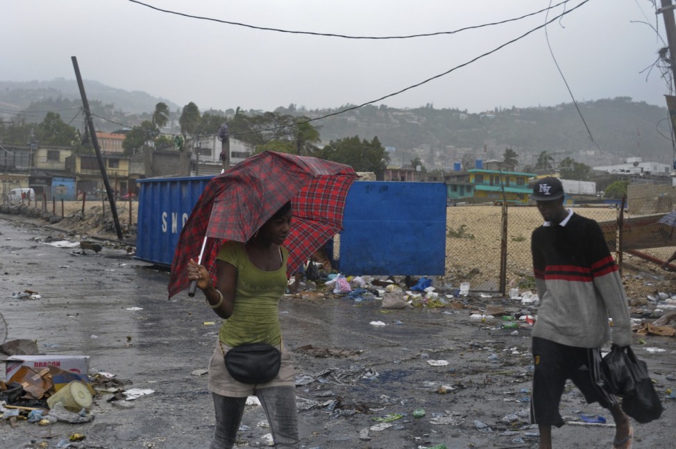 Haitian woman tries to shield herself from heavy rains of Tropical Storm Isaac with an umbrella in Port-au-Prince