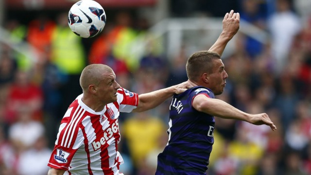 Arsenal's Podolski challenges Stoke City's Wilkinson during their English Premier League soccer match at the Britannia Stadium in Stoke-on-Trent