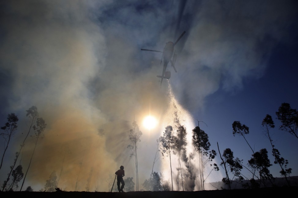 A helicopter drops water over a forest fire in Alvaiazere, near Ourem