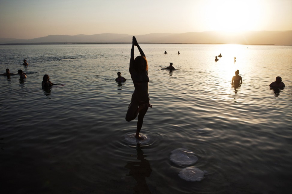 Woman practices yoga during a mass floating event in the Dead Sea