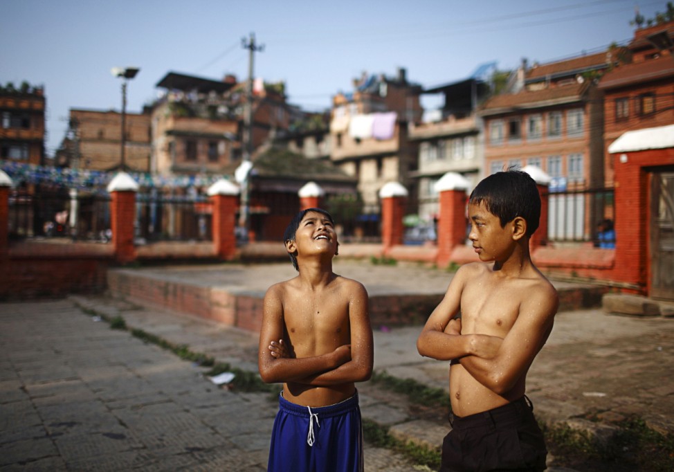 Boys bask in the sun after swimming in a pond at the premises of Baglamukhi Temple in Lalitpur