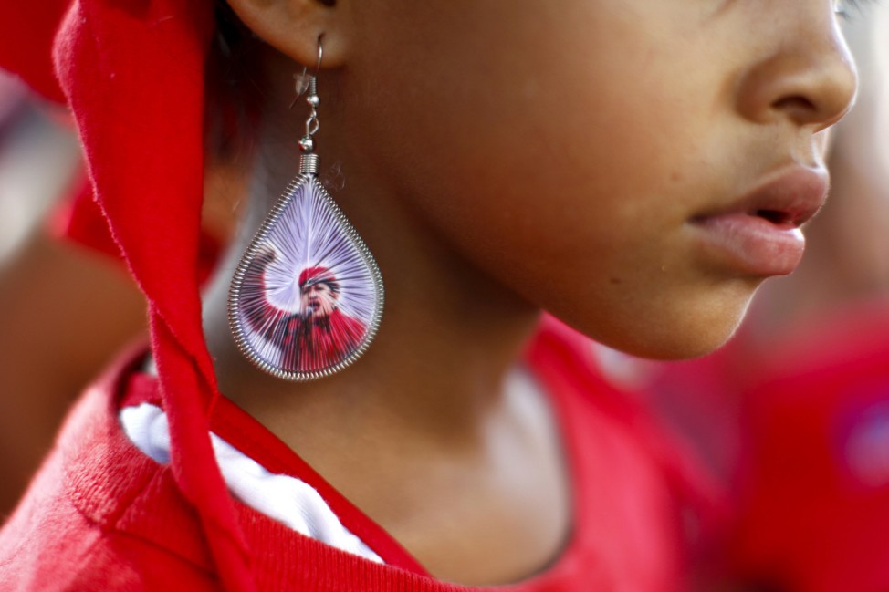 A girl wears an earring with a picture of Venezuela's President Hugo Chavez during Chavez's campaign rally in Guarenas