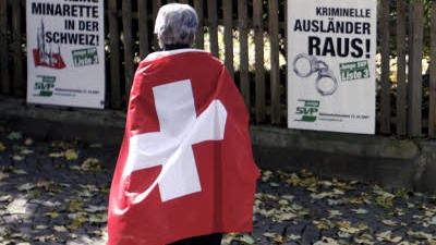 Nach Minarett-Verbot in der Schweiz: Eine Frau mit Schweizer Flagge vor SVP-Wahlplakaten: Weit und breit ist in der Schweiz niemand in Sicht, der den Rechtspopulisten in nächster Zeit Einhalt gebieten könnte.