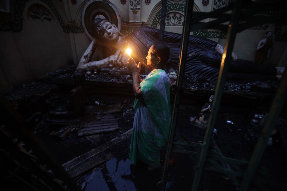 A Bangladeshi Buddhist woman prays in front of a burnt Buddha sculpture after Muslims attacked and set fire to the temple in Cox's Bazar