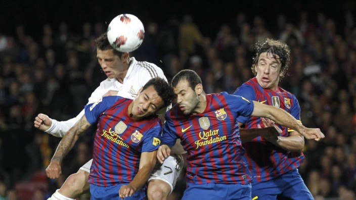 Real Madrid's Ronaldo heads the ball with Barcelona's Thiago, Mascherano and Puyol during their Spanish first division soccer match in Barcelona