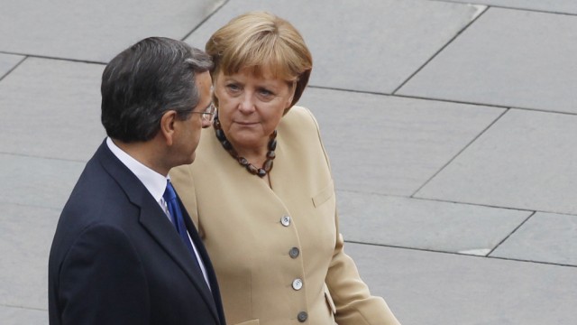 German Chancellor Angela Merkel gestures while standing with Greek Prime Minister Antonis Samaras as they inspect the honor guard before talks at the Chancellery in Berlin