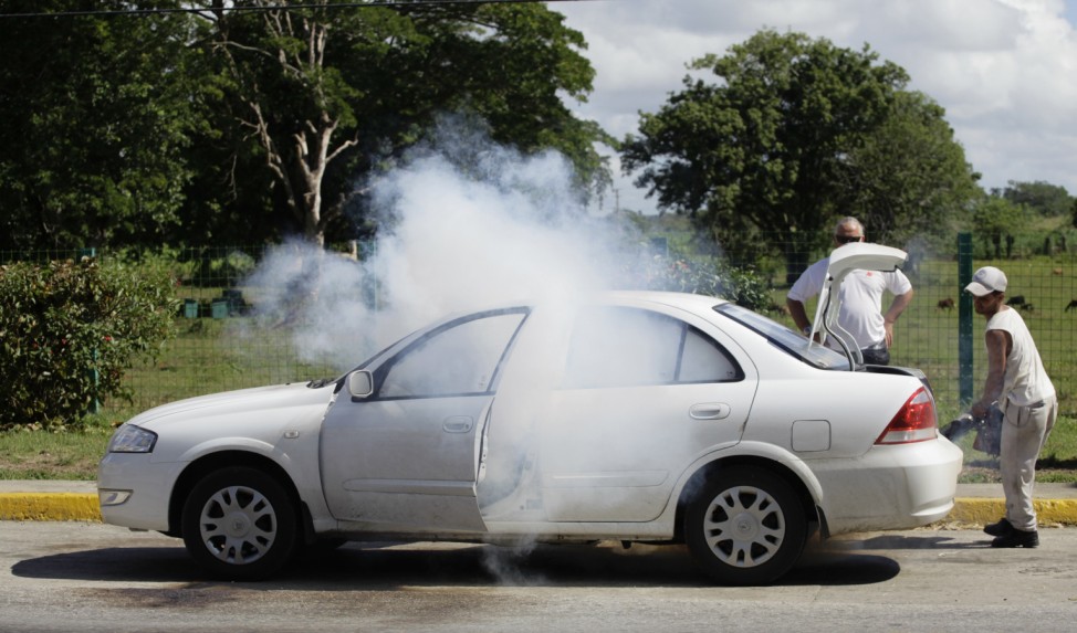 A health worker fumigates a car on the road in Jimaguayu near Camaguey in eastern Cuba