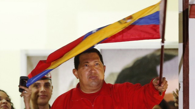 Venezuelan President Hugo Chavez waves the national flag while celebrating from a balcony at the Miraflores Palace in Caracas