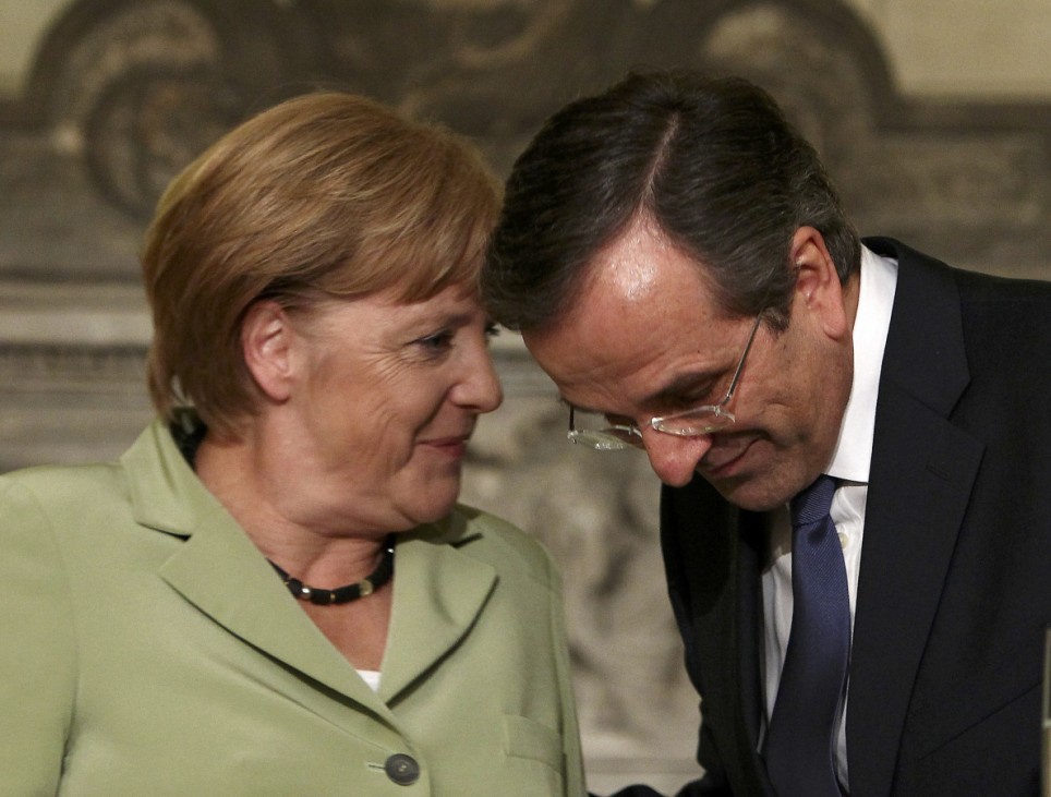 Greece's Prime Minister Antonis Samaras listens Germany's Chancellor Angela Merkel before their press conference at the Maximos mansion in Athens